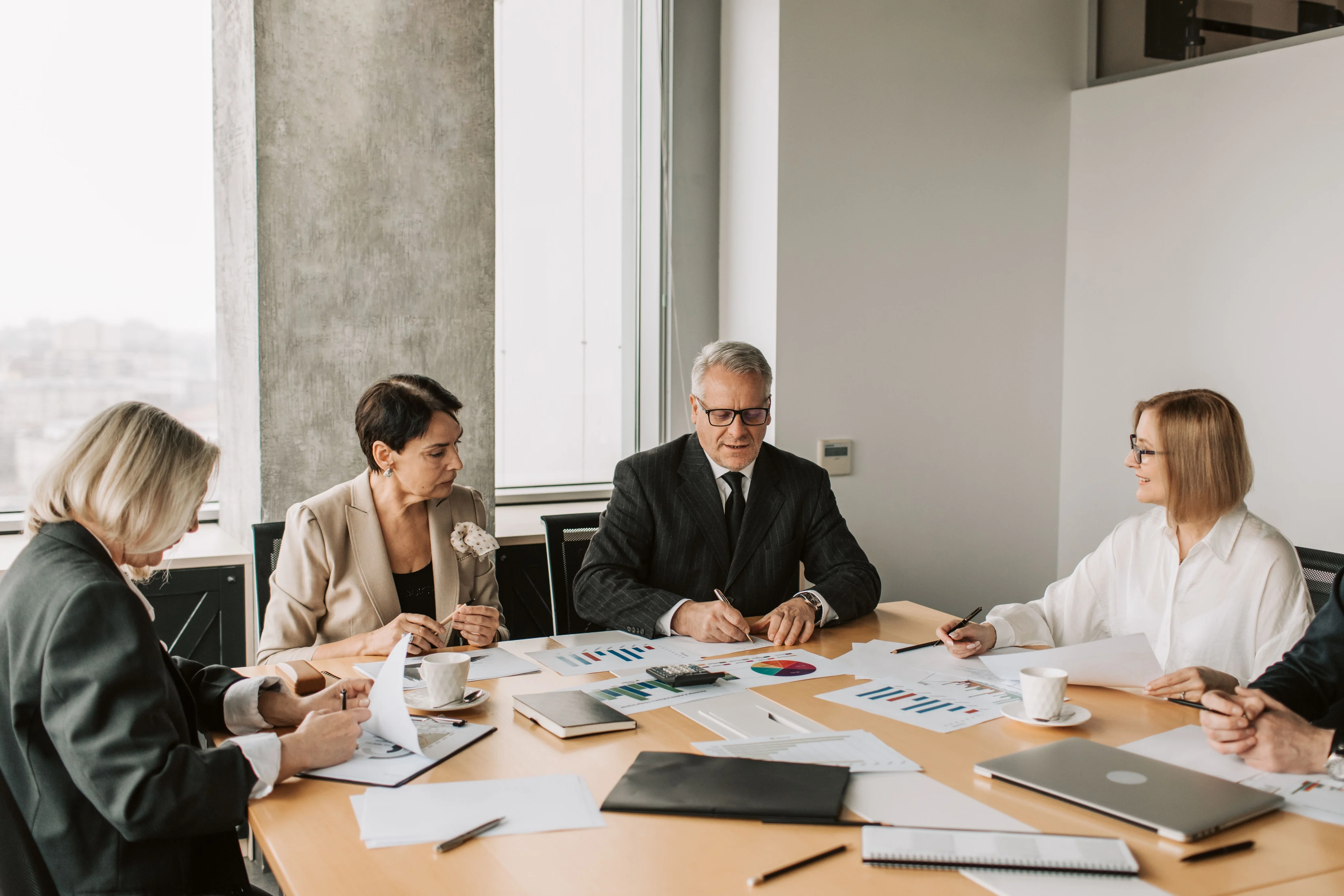 Senior professionals reviewing business charts around a corporate conference table